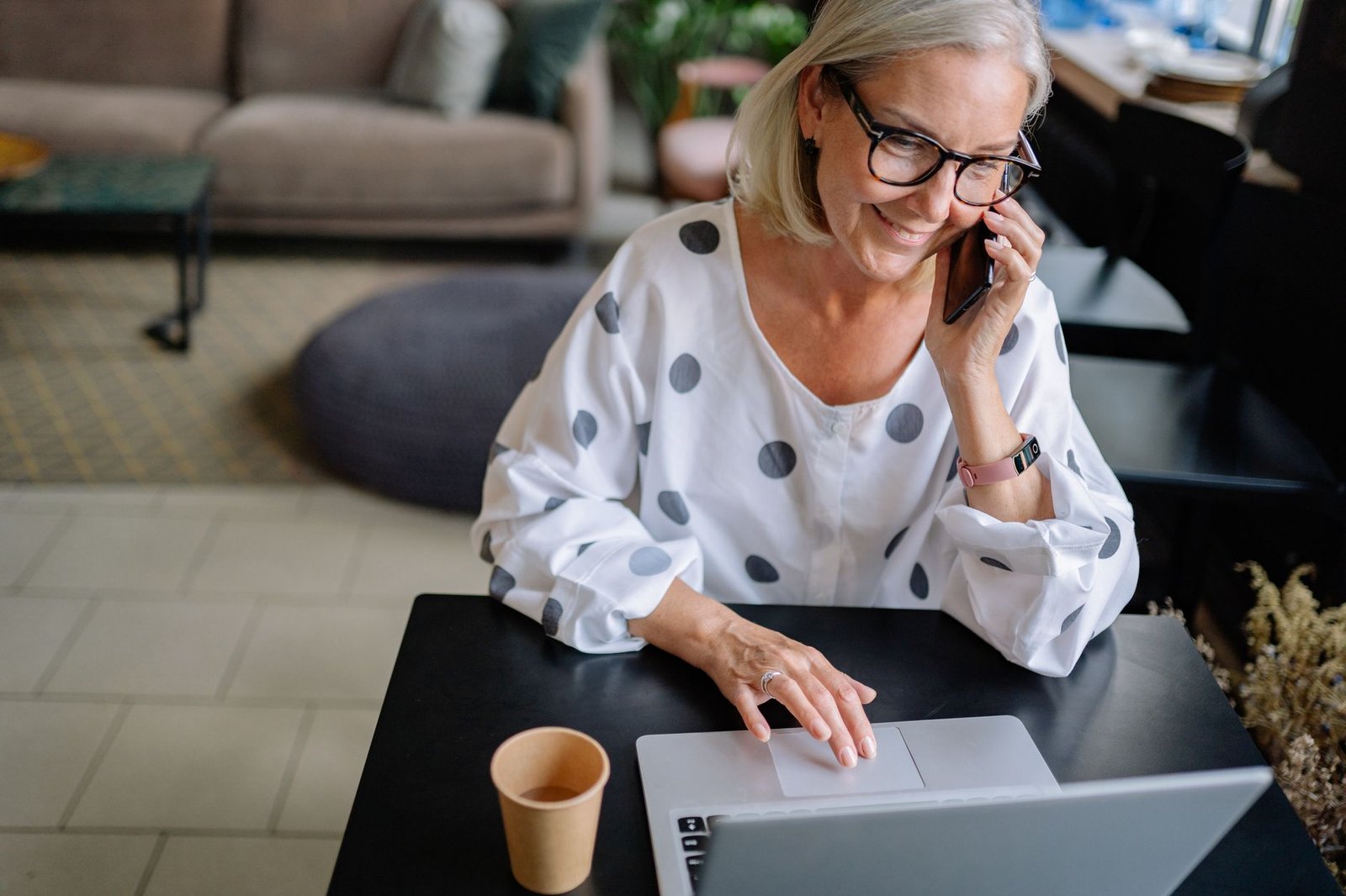 Person making a phone call while using a laptop at home
